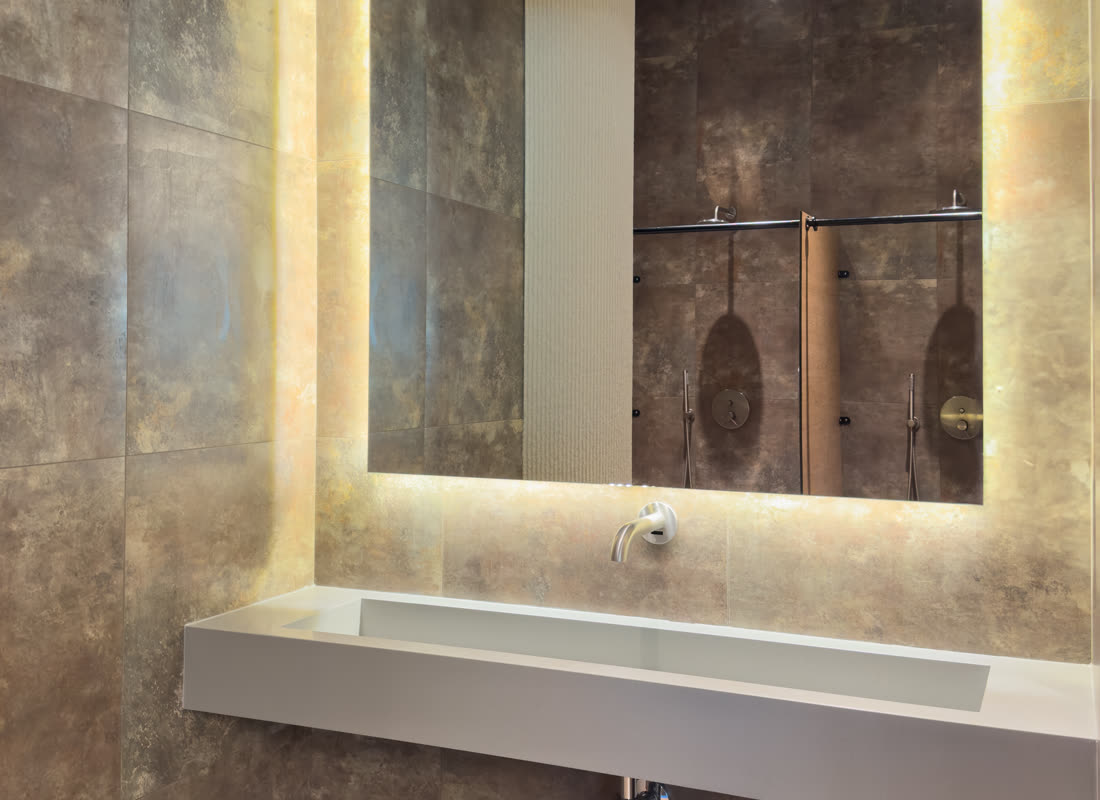 A finished bathroom with a backlit mirror and modern basin