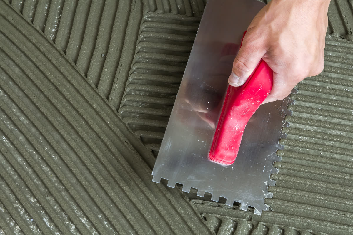 Adhesive combed out over a membrane before tile is laid