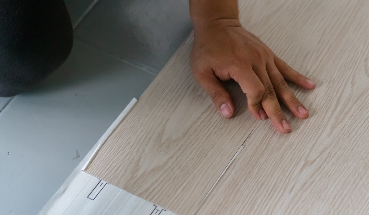 A fitter laying hardwood boards across a room