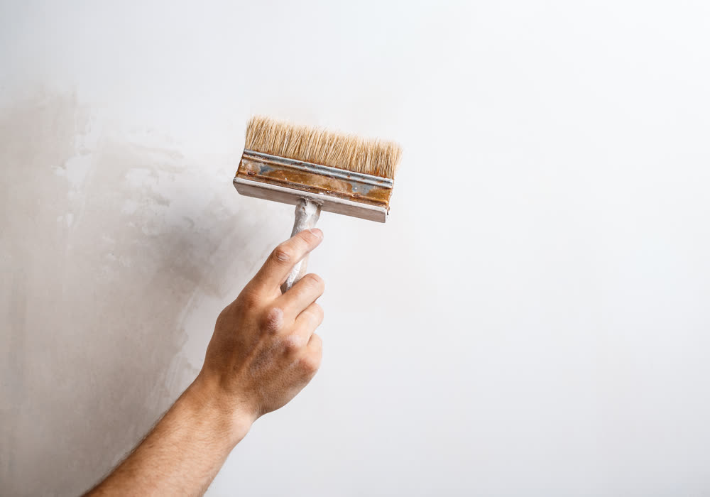 A brush cutting a clean paint line along the edge of a wall