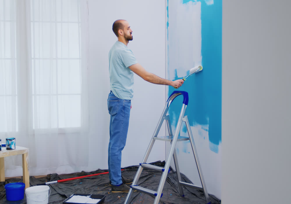 A painter rolling a full finish coat onto a prepared wall